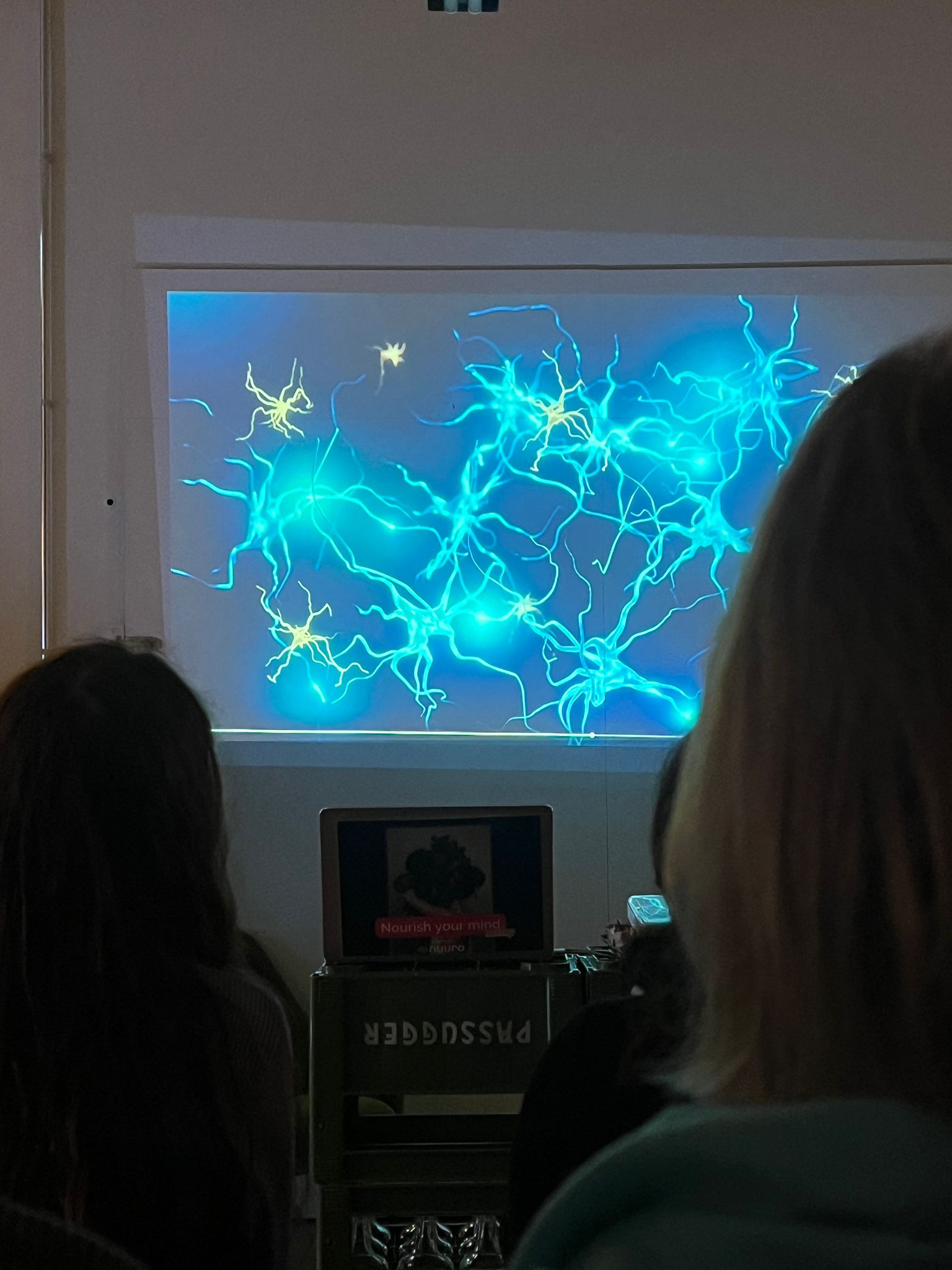 Neuron visualization projected during brain health presentation at Nourish Your Mind event